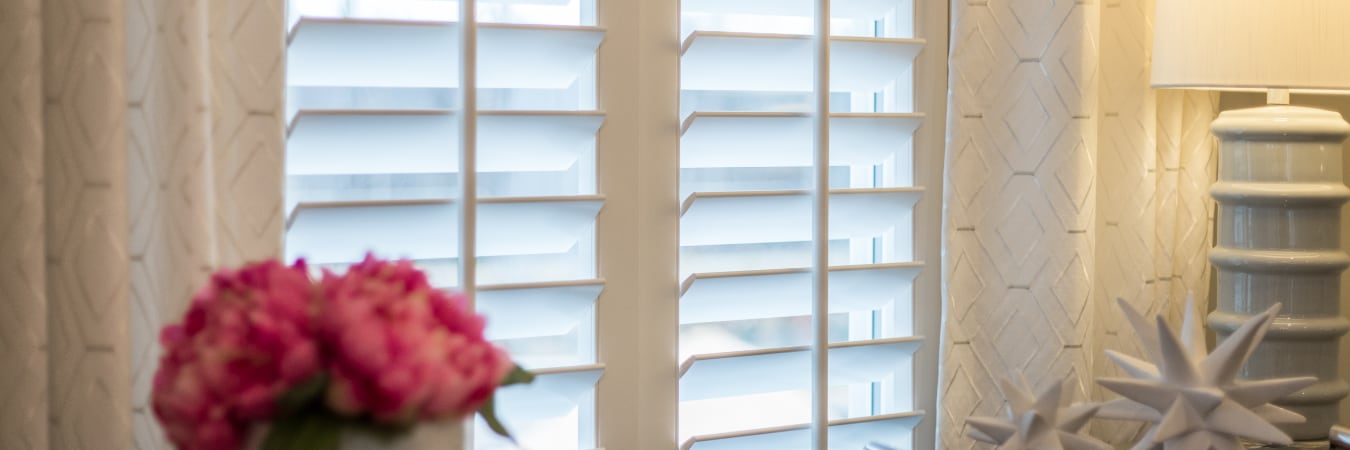 Plantation shutters layered with curtains.